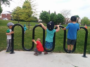 Playing on a bike rack at the park.